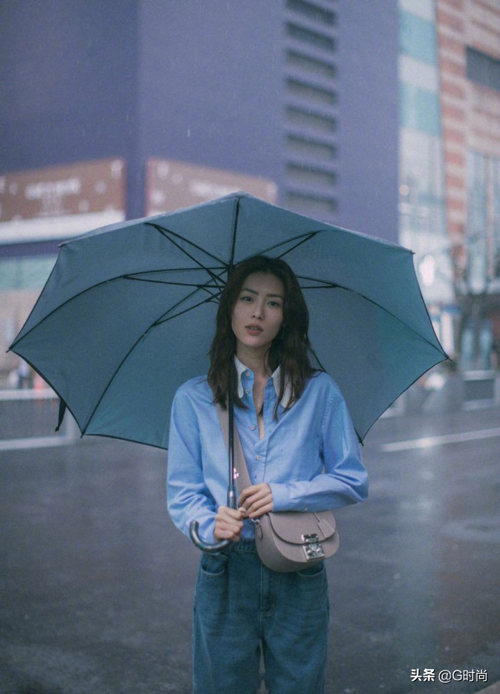 刘雯身穿蓝色衬衫搭配牛仔裤，漫步在雨中，清新悠闲时尚好看