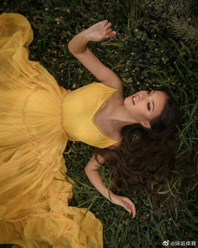 千金谢尔巴科娃穿着一身黄色公主裙，躺在草地上的画面唯美靓丽，让人怦然心动